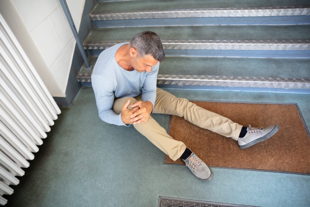 man sitting on ground holding knee